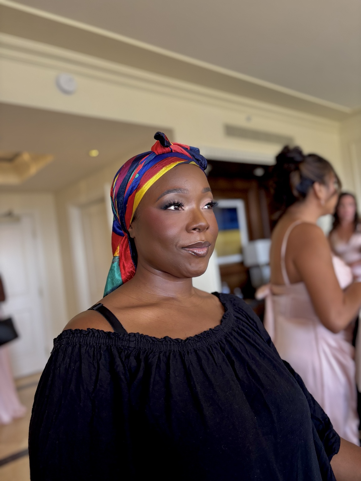 Finished makeup on a client with a deep complexion and floral head wrap